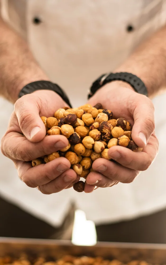 Le mani del gelatiere DiBe con una manciata di nocciole tostate
